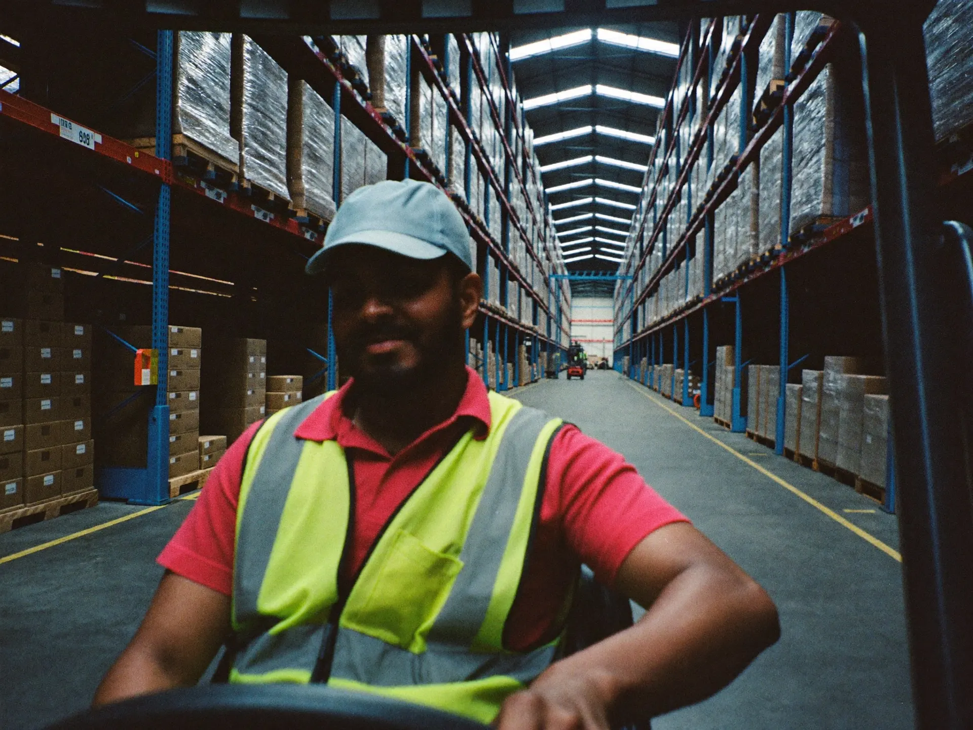 An Indian forklift operator moving pallets in a large warehouse