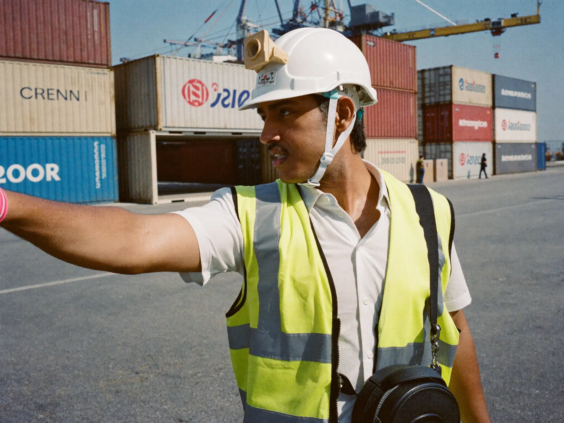 Indian port workers in hi-vis vests beside stacked containers at a terminal