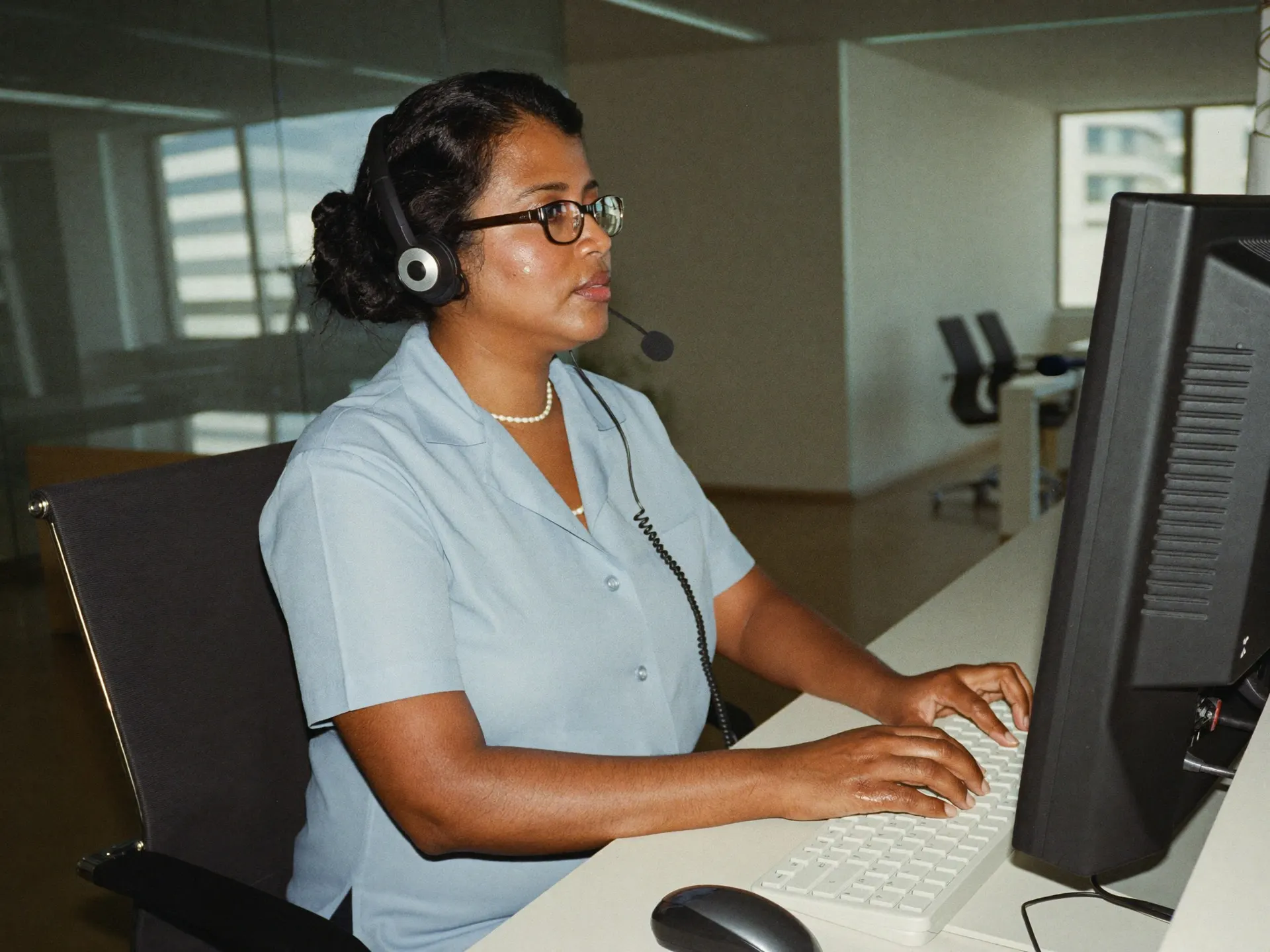 An Indian office administrator at a reception desk greeting a visitor