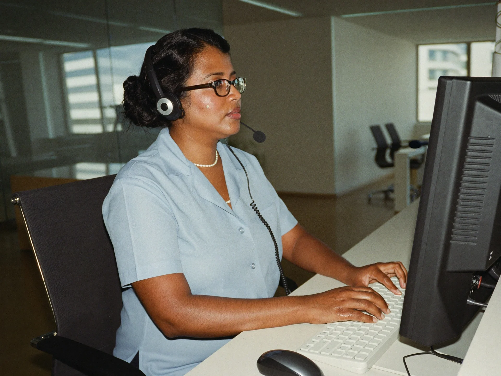 An Indian office administrator at a reception desk greeting a visitor